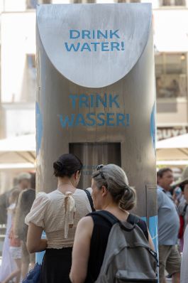 Personen stellen sich an einer Schlange an, um Wasser zu trinken. Schlagw&ouml;rter: Wasser, Innenstadt, Wasserflasche