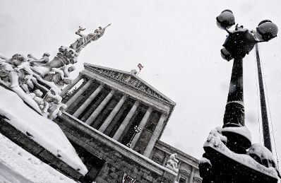 Eine winterliche Aufnahme des Parlamentsgeb&auml;udes mit dem Pallas Athene Brunnen davor. Schlagworte: Architektur, Brunnen, Denkmal, Geb&auml;ude, Schnee, Statue, Sehensw&uuml;rdigkeit, Stadtlandschaft, Winter
