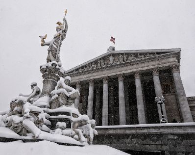 Eine winterliche Aufnahme des Parlamentsgeb&auml;udes mit dem Pallas Athene Brunnen davor. Schlagworte: Architektur, Brunnen, Denkmal, Geb&auml;ude, Schnee, Statue, Sehensw&uuml;rdigkeit, Stadtlandschaft, Winter
