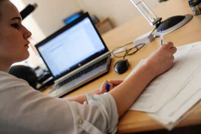 Eine Frau bei der Arbeit. Schlagworte: Arbeitsplatz, Bildschirm, Computer, schreiben, Wirtschaft