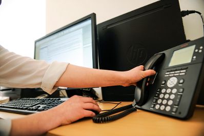 Eine Frau bei der Arbeit. Schlagworte: Arbeitsplatz, Bildschirm, Computer, Ger&auml;t, H&auml;nde, Tastatur, Technik, Telefon, Wirtschaft