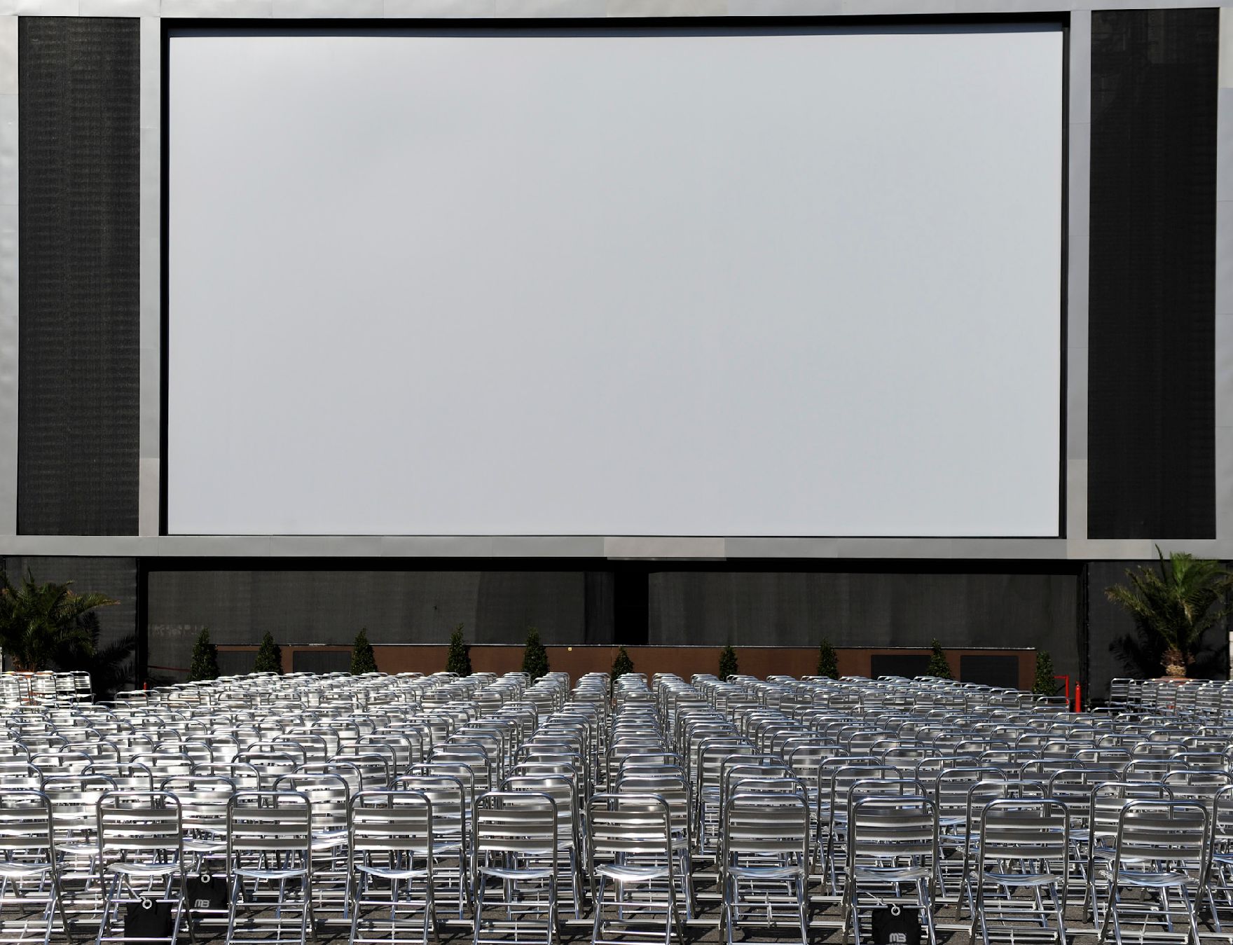 Leere Aluminiumsesselreihen vor einer großen Leinland beim Filmfestivals am Rathausplatz. Schlagworte: Kultur, Kunst, Musik, Sessel, Stuhl, Stühle