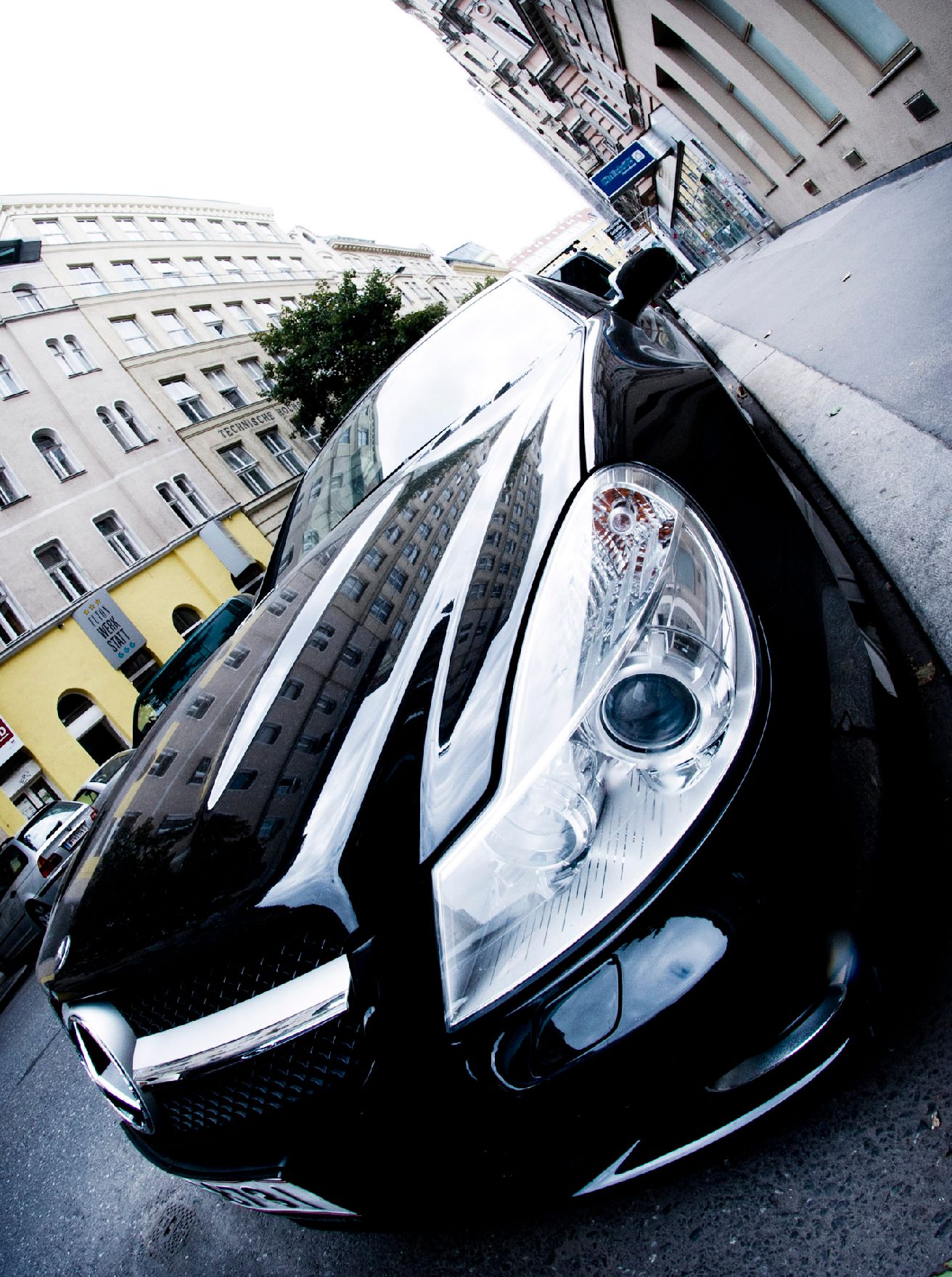 Ein parkender, schwarzer Mercedes. Schlagworte: Auto, Fahrzeug, PKW, Scheinwerfer, Stadtlandschaften, Verkehr