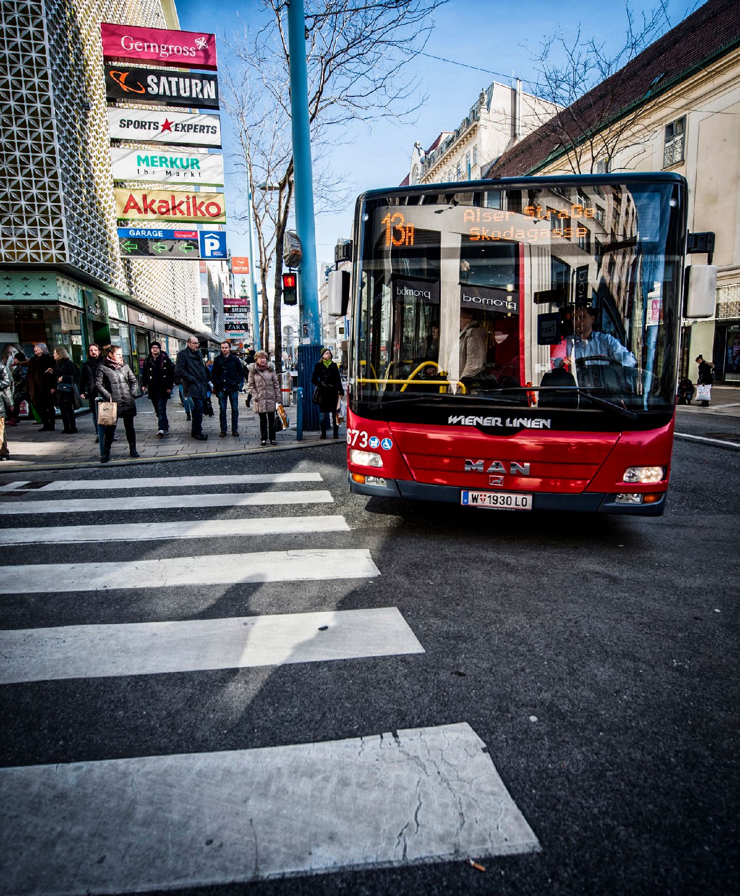 Ein Autobus auf der Mariahilferstraße. Schlagworte: Ampel, Geschäfte, Menschen, Straße, Stadtlandschaften, Verkehr, Zebrastreifen