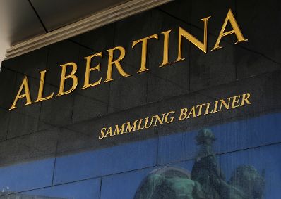 Schild "ALBERTINA SAMMLUNG BATLINER" mit einer Spiegelung der Reiterstaue vor dem Museum. Schlagworte: Beschriftung, Museum, Schild