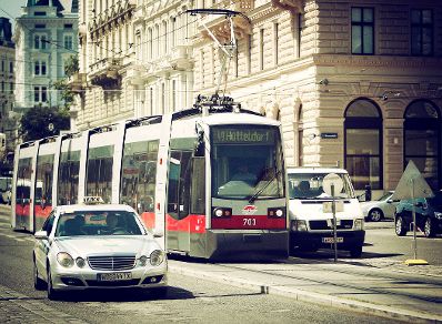 Eine befahrene Straße in Wien. Schlagworte: Autos, Fahrzeuge, Schiene, Stadtlandschaften, Straße, Straßenbahn, Taxi, Verkehr, Wiener Linien